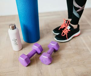 Minimalist training equipment like a yoga mat and water bottle in a dark room