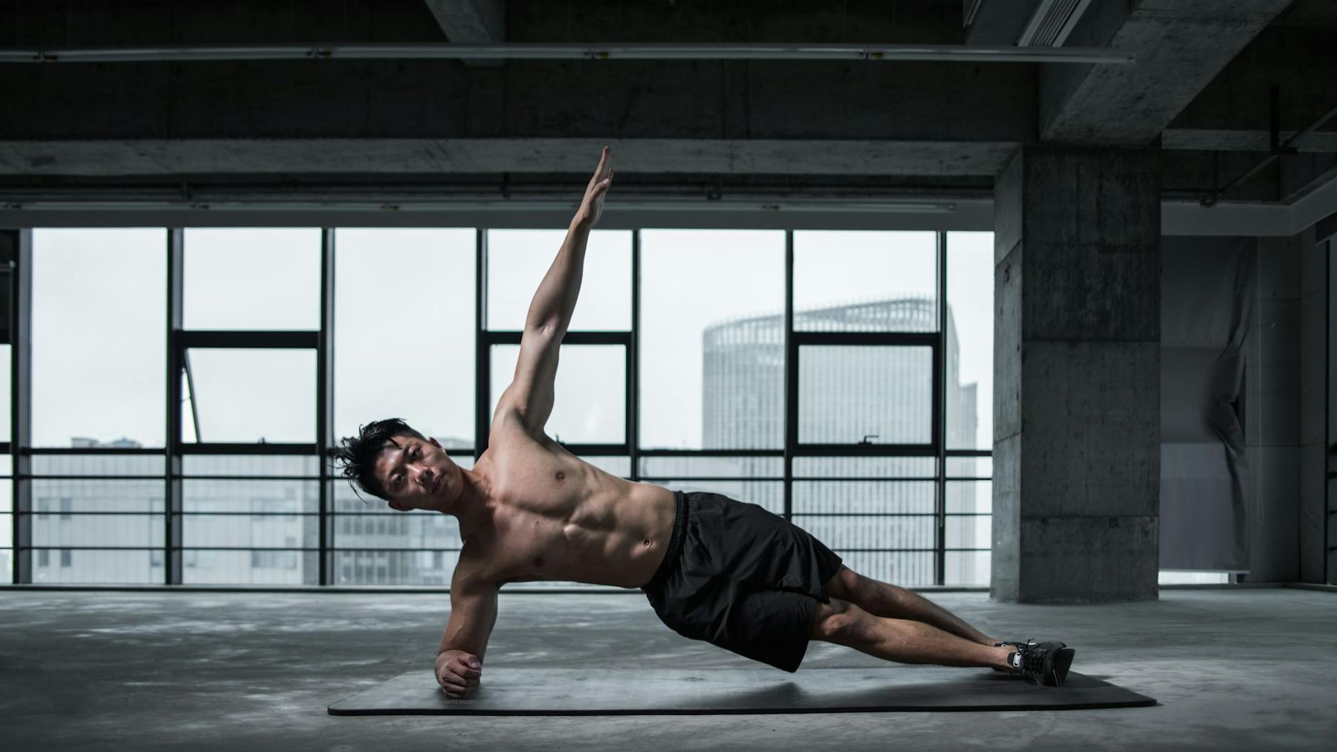 Strong man focusing on core stability exercises in a modern dark gym environment